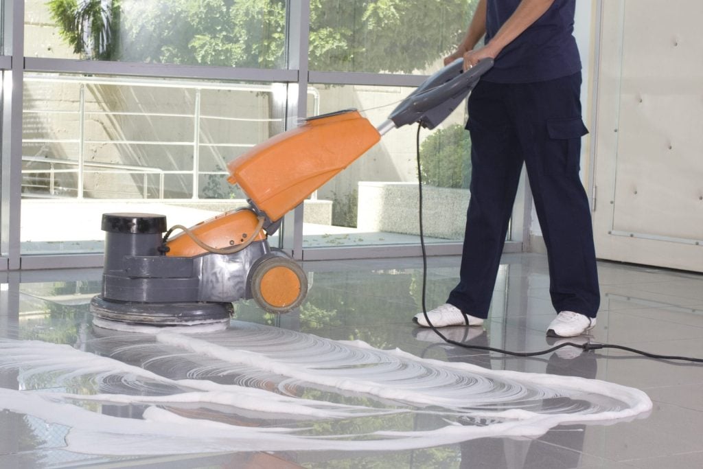 Kamloops office cleaning services - partial body of person using an orange floor polishing machine