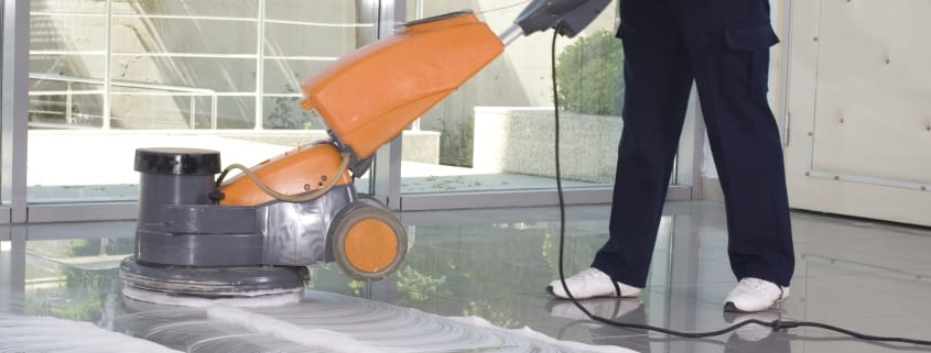 Kamloops office cleaning services - partial body of person using an orange floor polishing machine