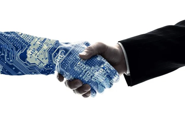 A human hand in a business suit shakes hands with a robotic hand made of blue computer circuitry, symbolizing partnership between technology and humans.