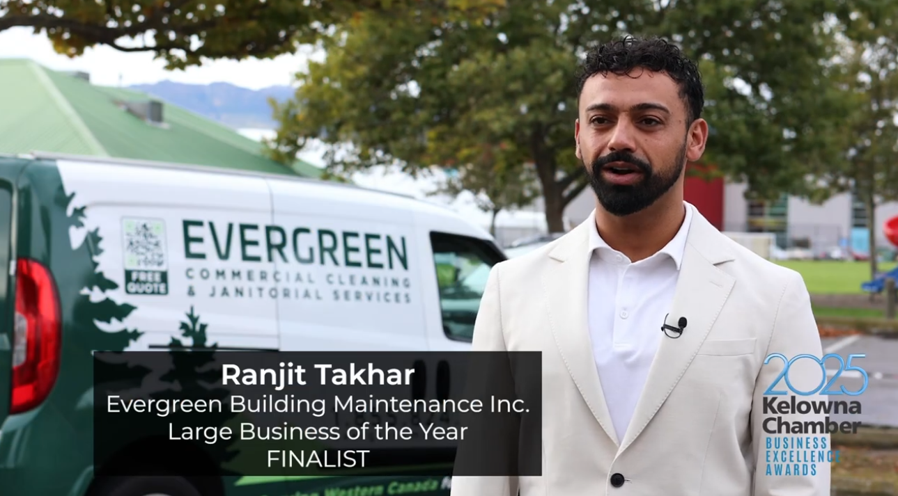 A man in a cream suit stands outdoors before an Evergreen Kelowna commercial cleaning van. Text reads “Ranjit Takhar, Evergreen Building Maintenance Inc., Large Business of the Year FINALIST. 2025 Kelowna Chamber Business Excellence Awards.”.
